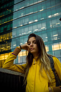 Beautiful woman standing against yellow building