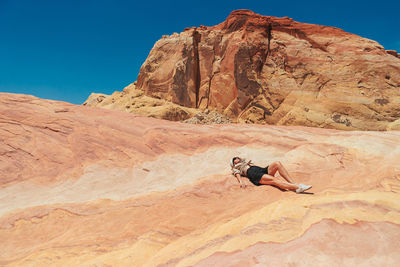 Rear view of man standing on mountain against clear blue sky