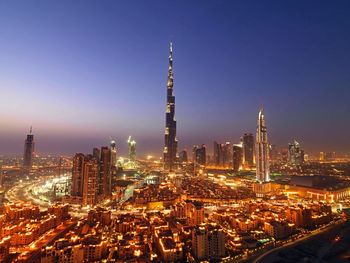 Illuminated burj khalifa and cityscape against clear sky at dusk