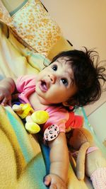 Close-up of cute baby girl on bed at home