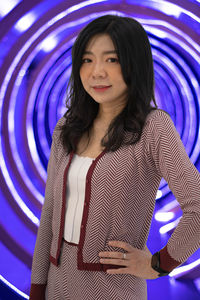 Portrait of young asian woman standing against colorful circle lights background