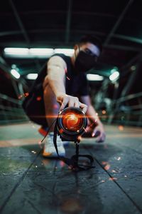 Low angle view of young man photographing with illuminated camera