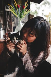 Smiling woman playing with cat at home