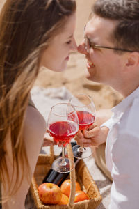 Side view of couple holding wine embracing outdoors