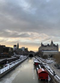 View of buildings at waterfront against cloudy sky