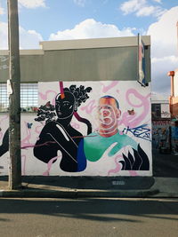 Graffiti on wall by street against sky in city