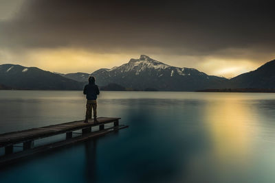 Man standing on lake against mountains