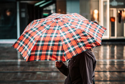 Midsection of woman holding umbrella on street in rainy season
