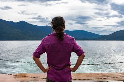 Rear view of woman standing on mountain against sky