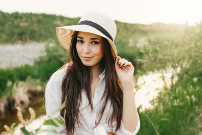 Portrait of beautiful young woman by plants against sky