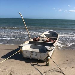 Ship moored on beach against sky