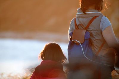 Rear view of mother with daughter standing by sea