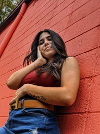 Portrait of a young woman sitting against wall