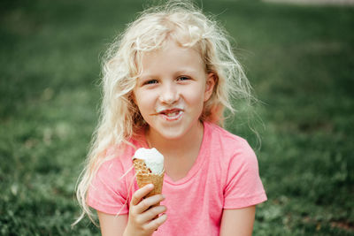 Cute funny girl with dirty nose and milk moustaches eating licking ice cream from waffle cone. 