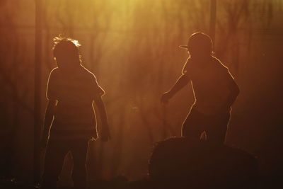 Boys playing in field during sunset