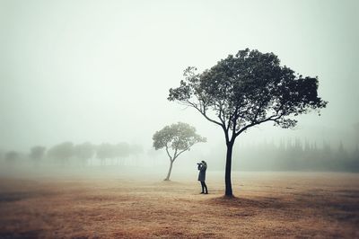 Mid distance view of woman standing on field during foggy weather