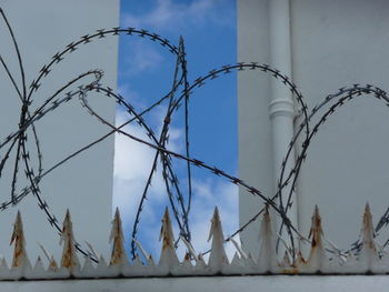 Low angle view of barbed wire fence against sky