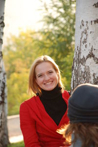 Portrait of young woman standing against trees