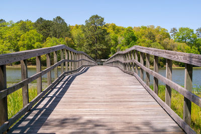 Wooden footbridge in forest against clear sky