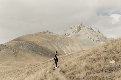 Rear view of woman walking on mountain against sky