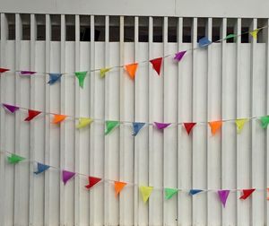 Multi colored bunting flags decorated against metal gate