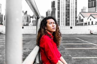 Portrait of beautiful woman standing by railing in city