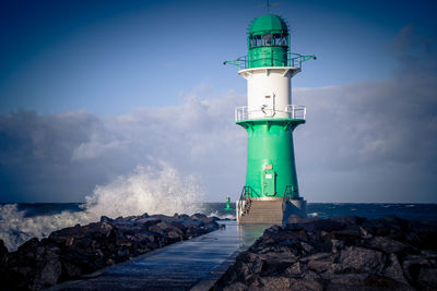 Lighthouse by sea against sky