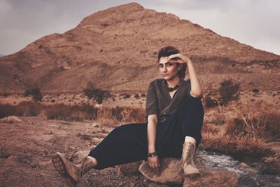 Full length of young woman sitting on land