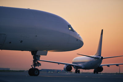 Cargo airplane is taxiing behind passenger airplane during morning busy traffic to airport runway.