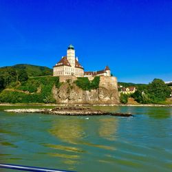 Castle by sea against blue sky