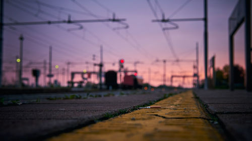 Surface level of railroad tracks against sky during sunset