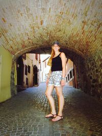 Portrait of woman standing in covered alley