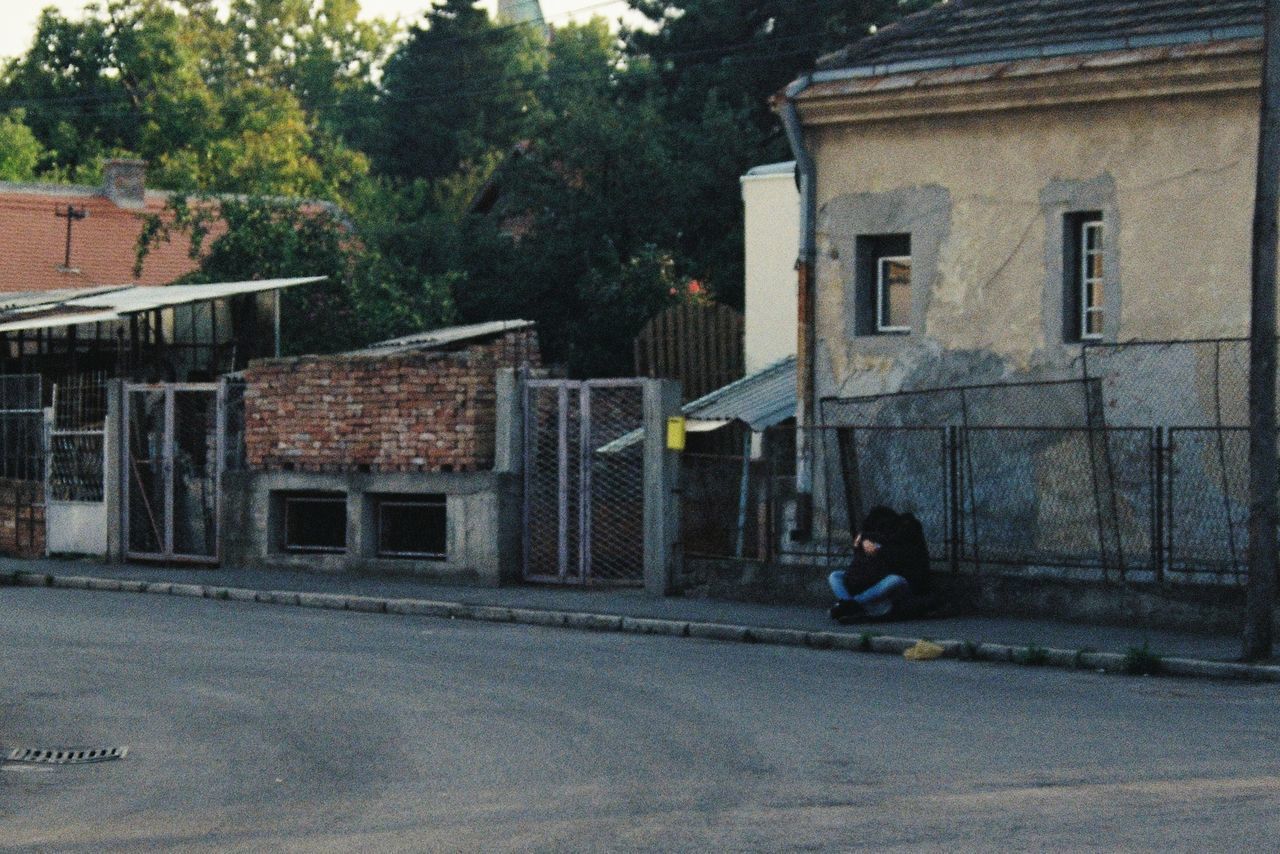 MAN WALKING ON ROAD ALONG BUILDINGS