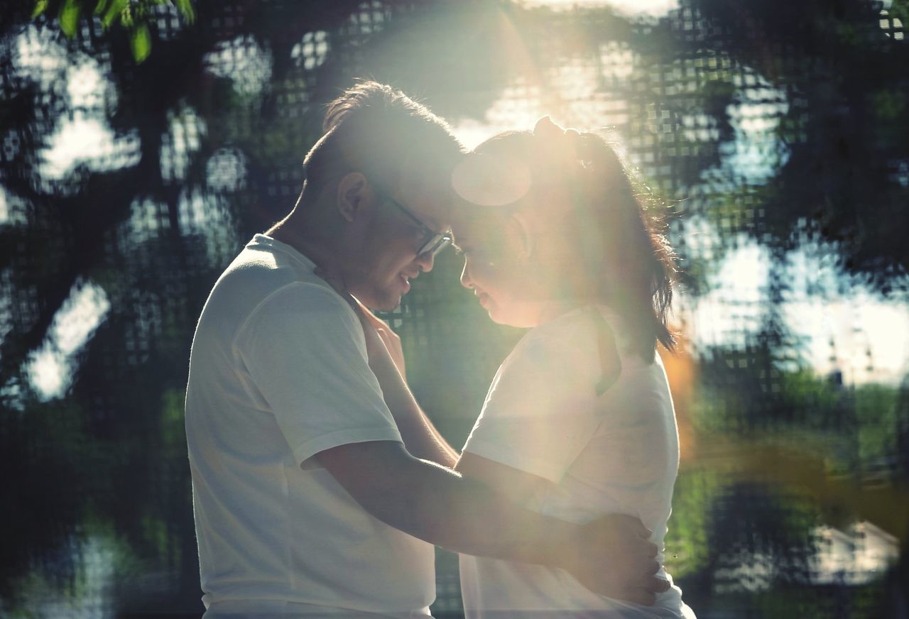 two people, adult, togetherness, men, kissing, sunlight, love, lens flare, young adult, nature, women, positive emotion, bonding, emotion, tree, romance, back lit, person, day, standing, outdoors, casual clothing, lifestyles, plant, waist up, happiness, embracing, female, clothing, side view, water, friendship, affectionate, summer, sunbeam