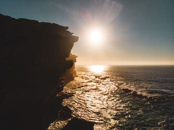 Rock formations in sea against sky during sunset