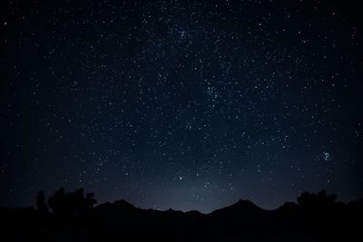 Low angle view of silhouette mountain against star field