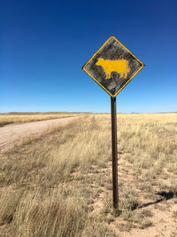 Road sign on land against clear sky