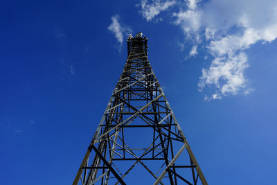 Low angle view of communications tower against blue sky during sunny day