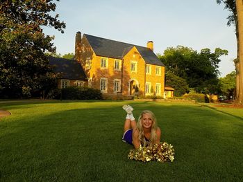 Woman with umbrella on lawn by building