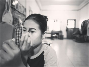 Young woman applying make-up at home