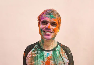 Portrait of indian man covered in holi colors against plain background 