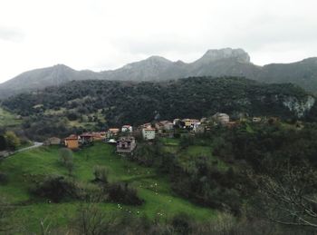 Houses on field by mountains against sky