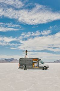 Young man standing on roof of camper van in bonneville salt flats.