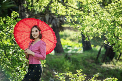Portrait of woman with pink umbrella standing in rain