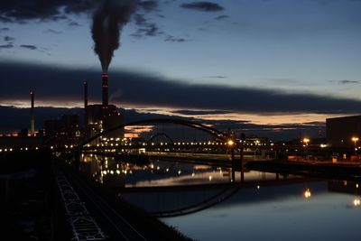 Factories emitting smoke against sky during dusk