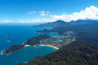 Aerial view of sea and mountains against blue sky