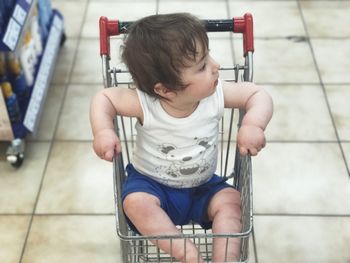 High angle of baby boy sitting in shopping cart