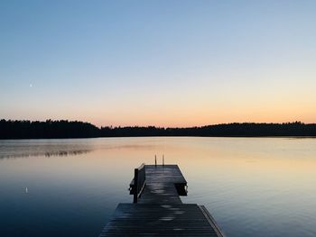 Pier on lake against sky during sunset