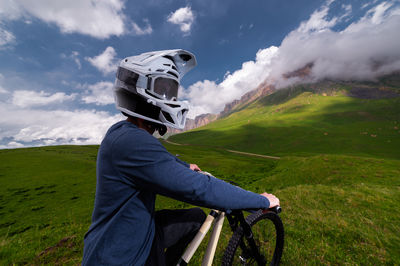 Rear view of young stunt biker preparing for stunt, high jump in alpine mountains. off-road riding