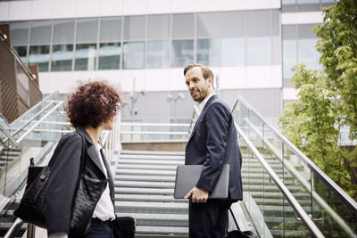 Low angle view of lawyer talking to coworker while standing on steps at office
